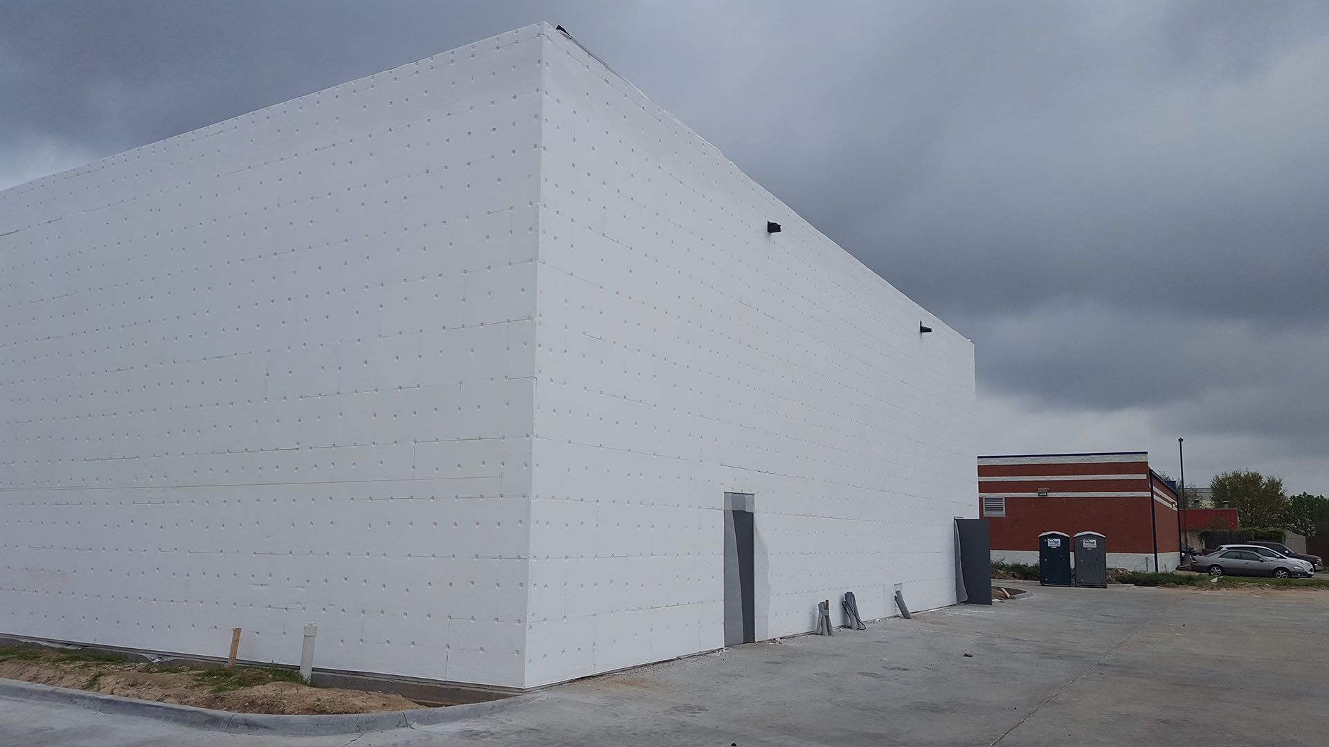 A large white building is being built on a cloudy day.