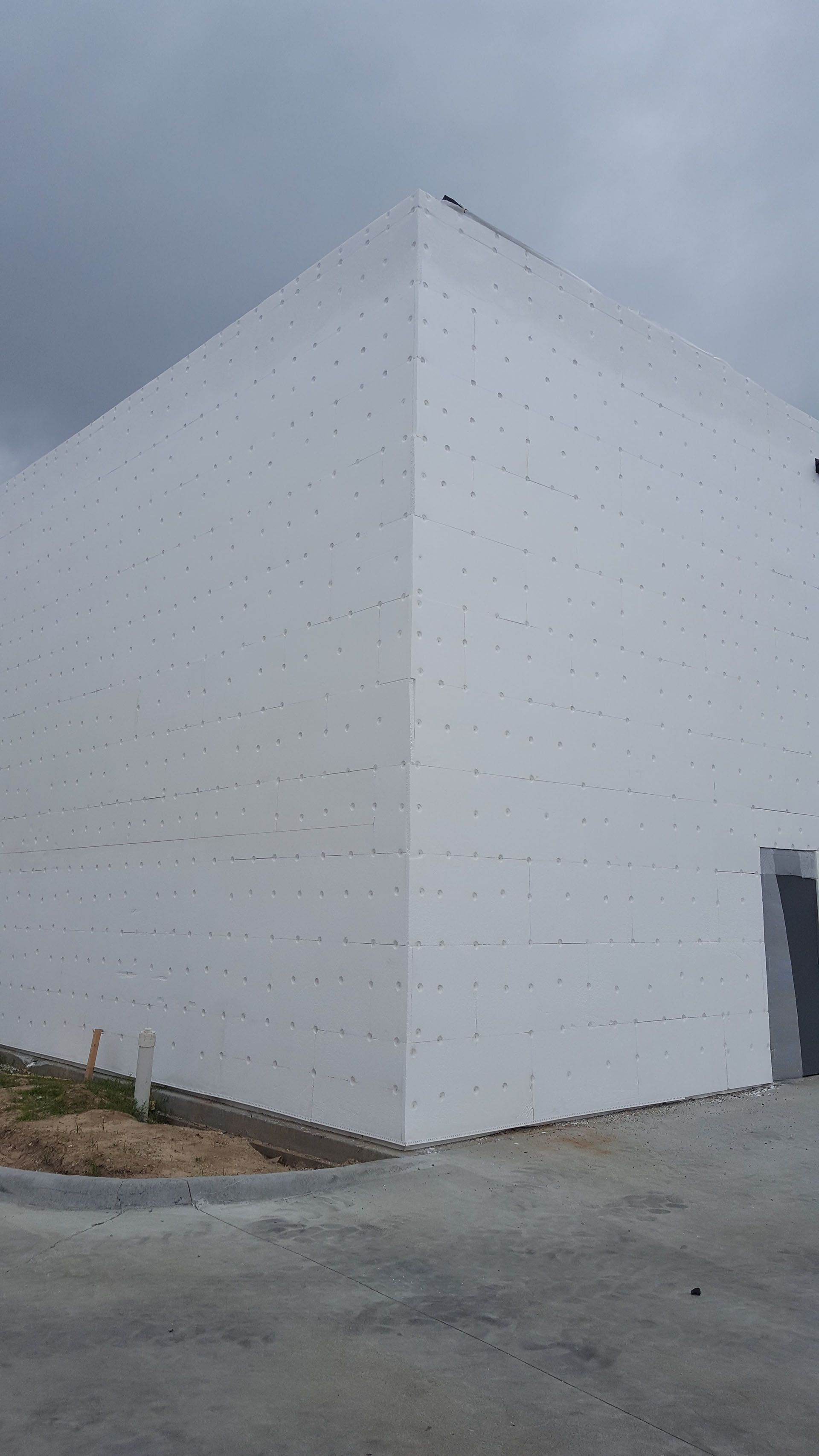 A large white building with a pyramid shaped roof is being built.