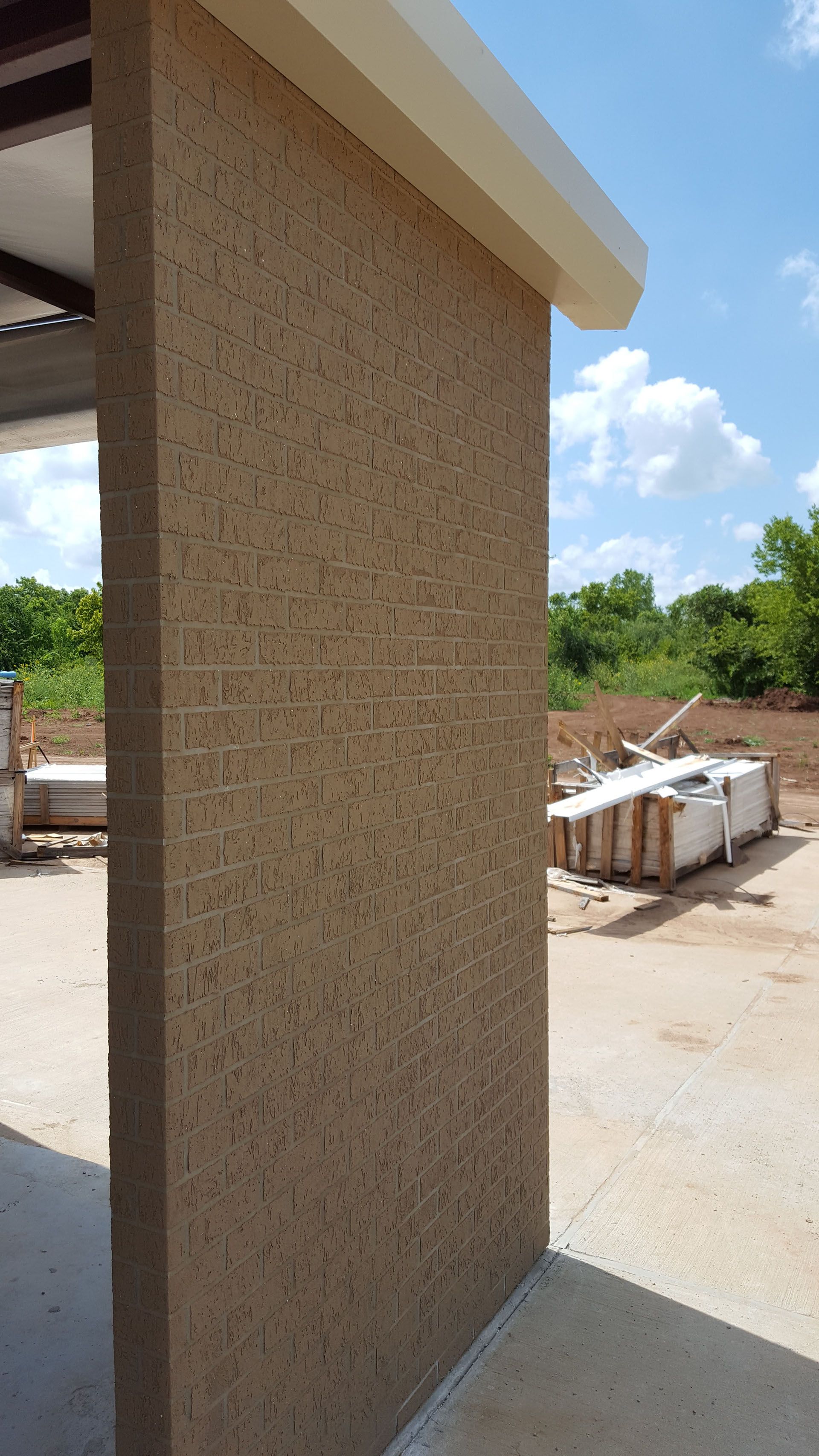 A corner of a building with a brick wall and a roof.
