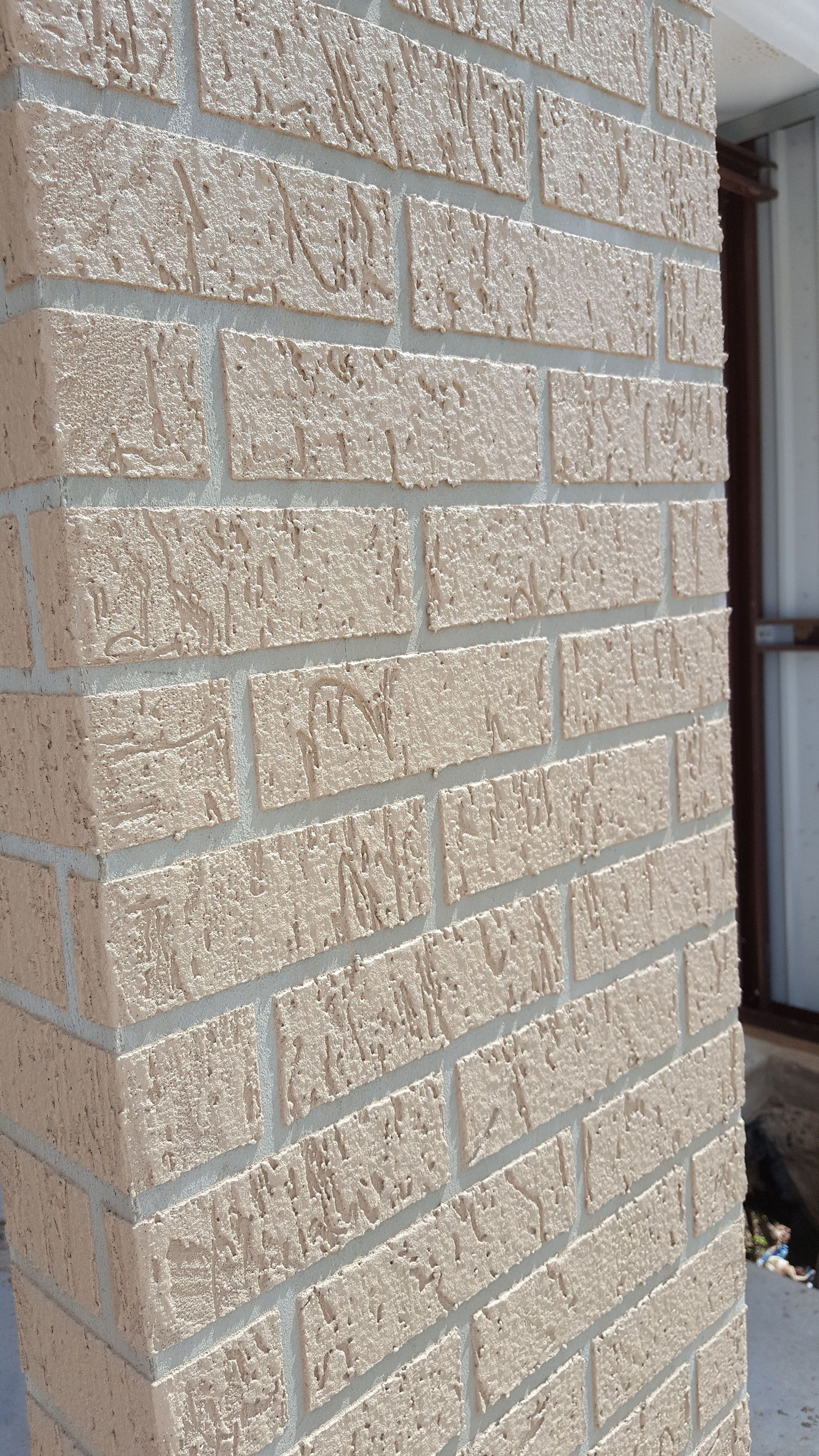 A close up of a brick wall with a window in the background.