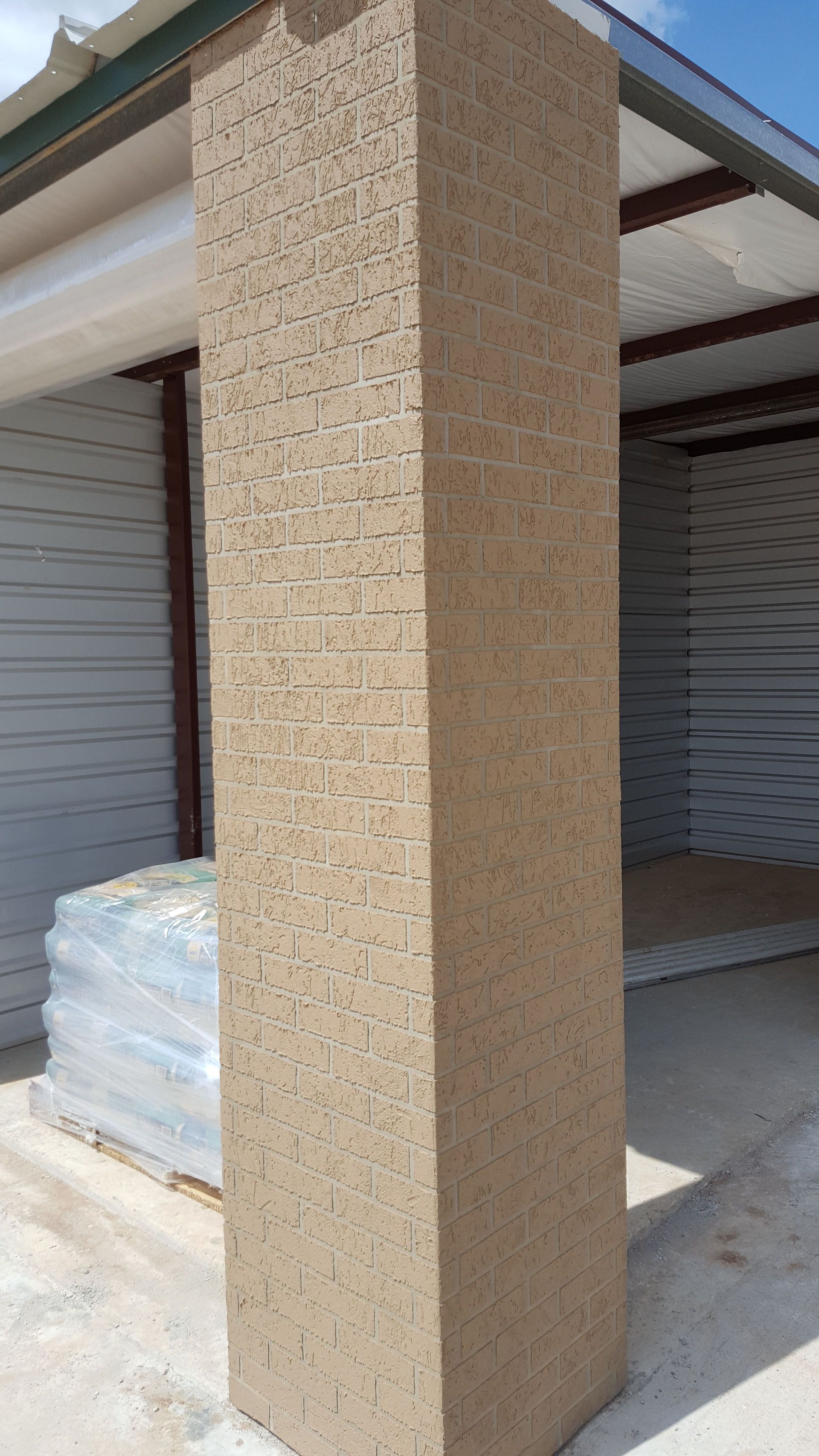A large pillar is sitting in front of a white building.