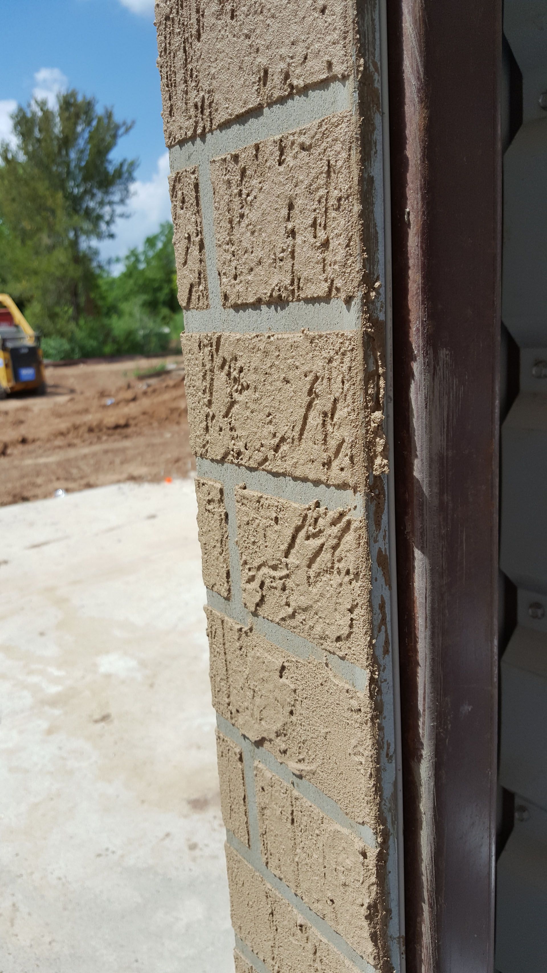 A close up of a brick wall with a door in the background.