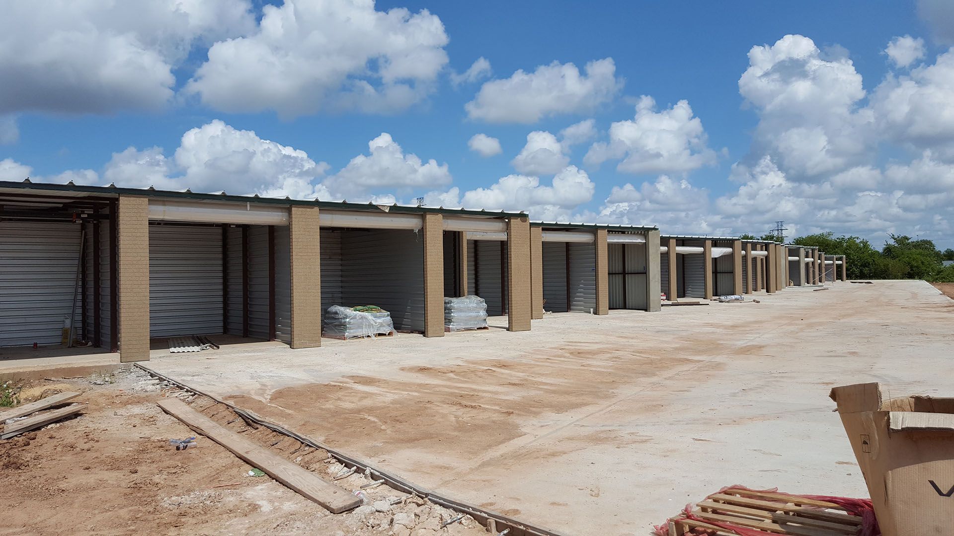 A row of buildings are being built on a dirt road.