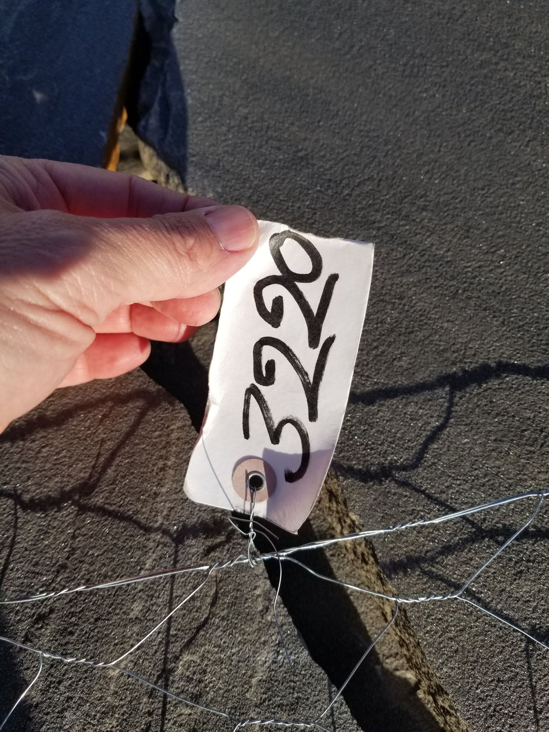 A person is holding a tag with the number 3220 on it