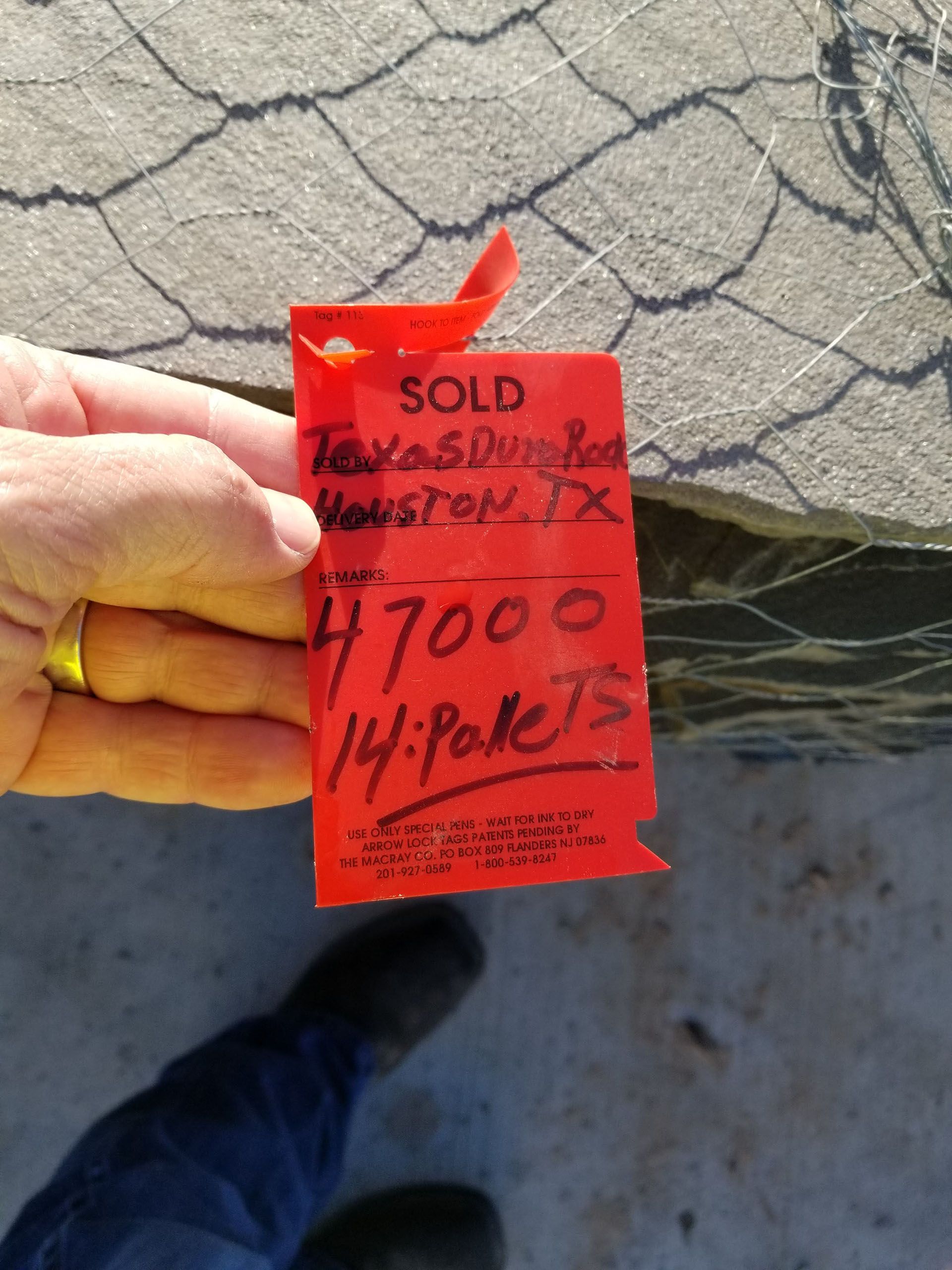 A person holding a red tag that says sold on it