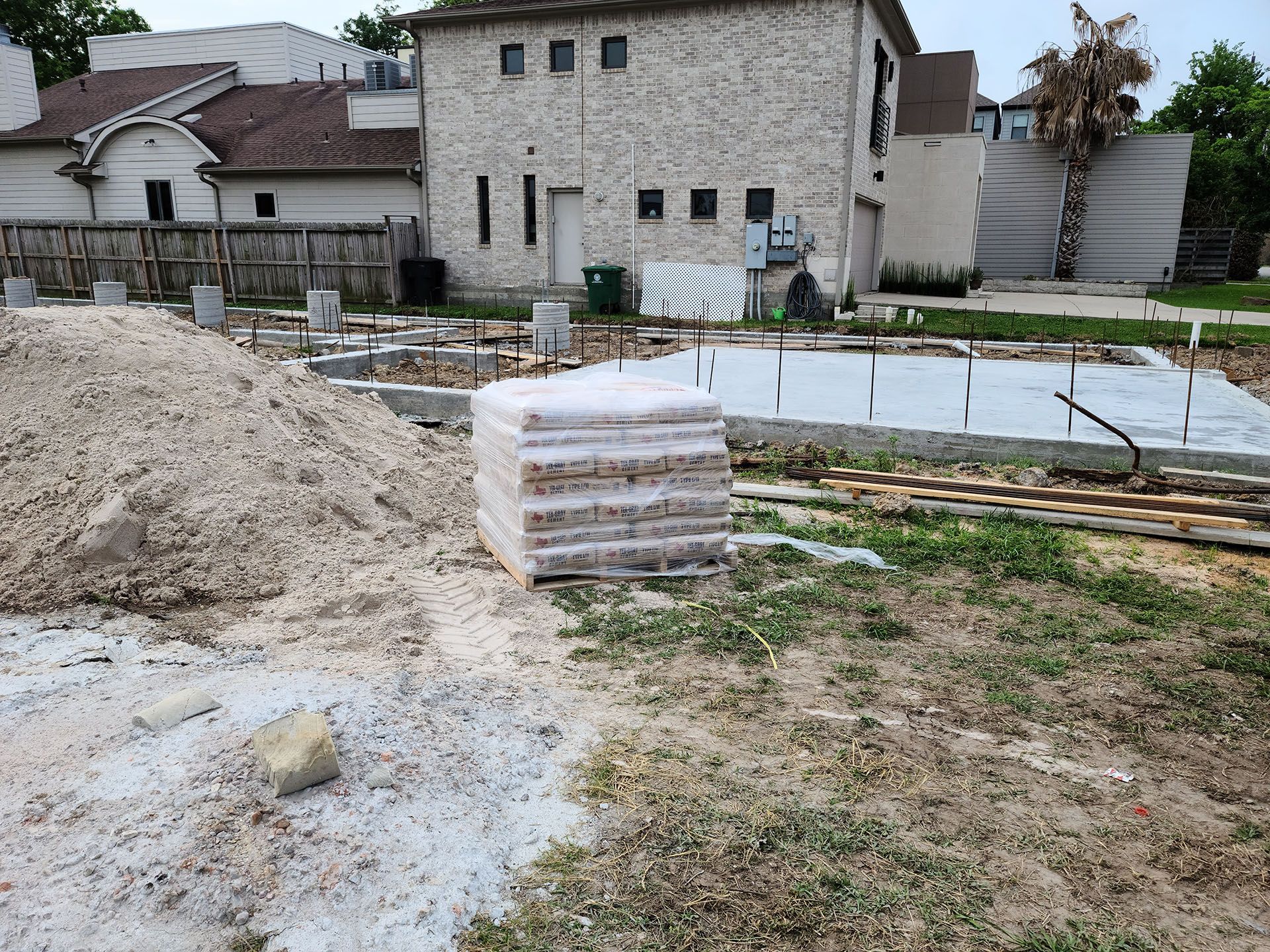 A pile of sand is sitting in front of a house under construction.