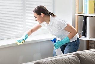 Housekeeper cleaning room with towel and spray
