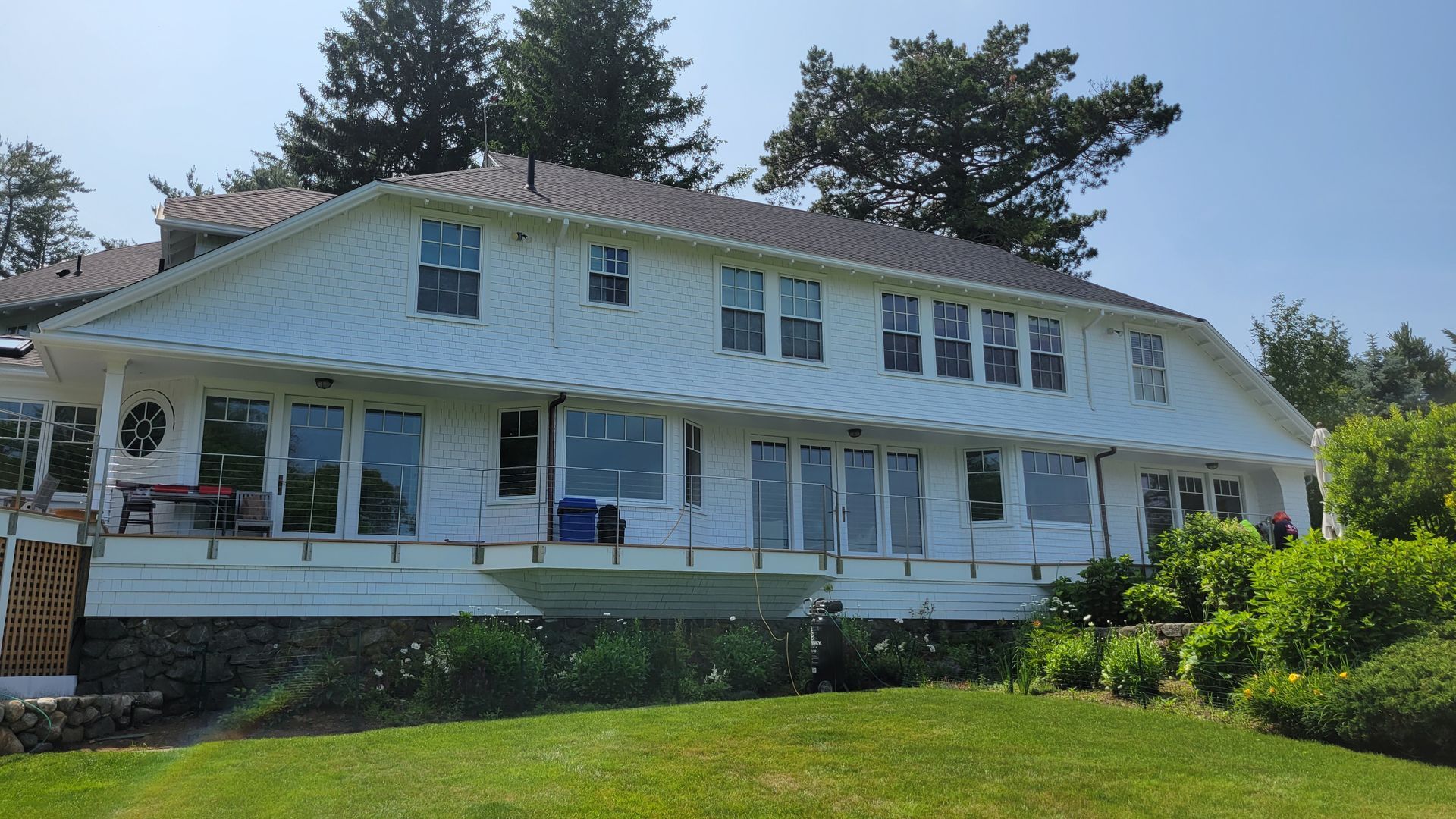 A large white house is sitting on top of a lush green hillside.