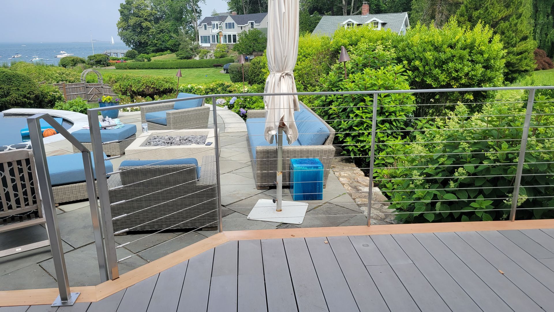 A patio with a stainless steel railing and a view of the ocean.