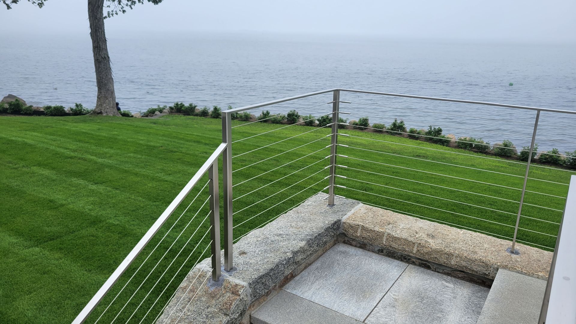 A view of the ocean from a balcony with a stainless steel railing.