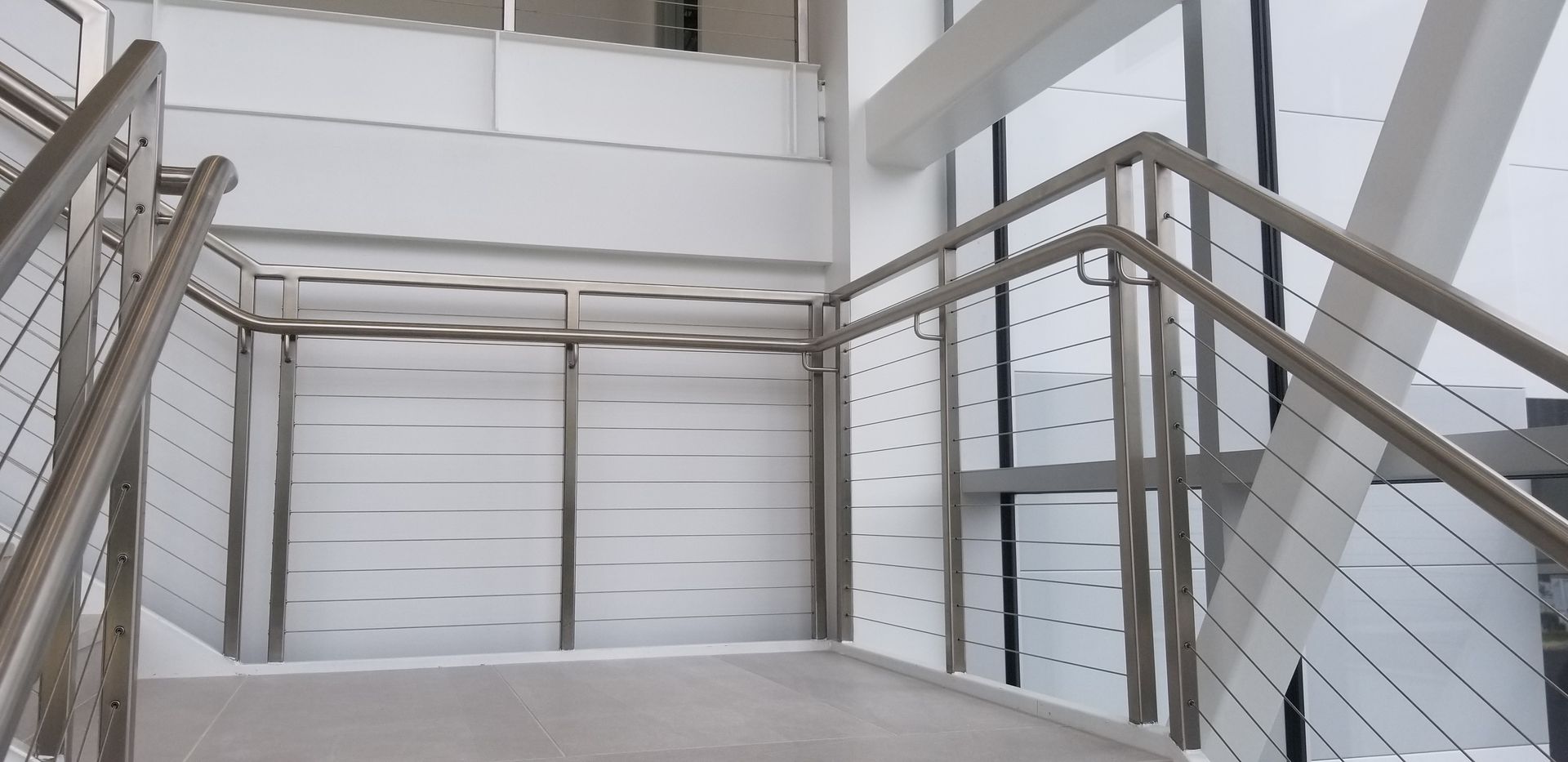 A staircase in a building with a stainless steel railing