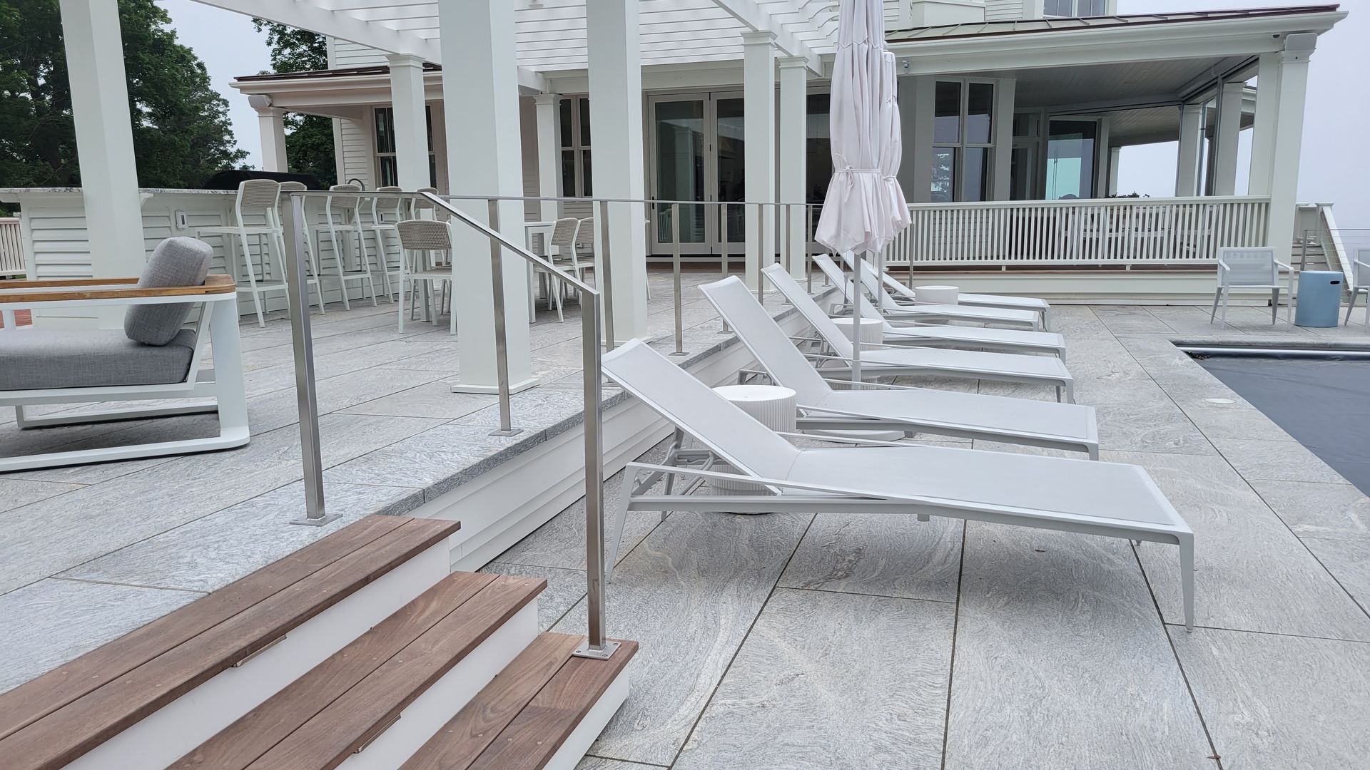 A row of lounge chairs are lined up next to a swimming pool