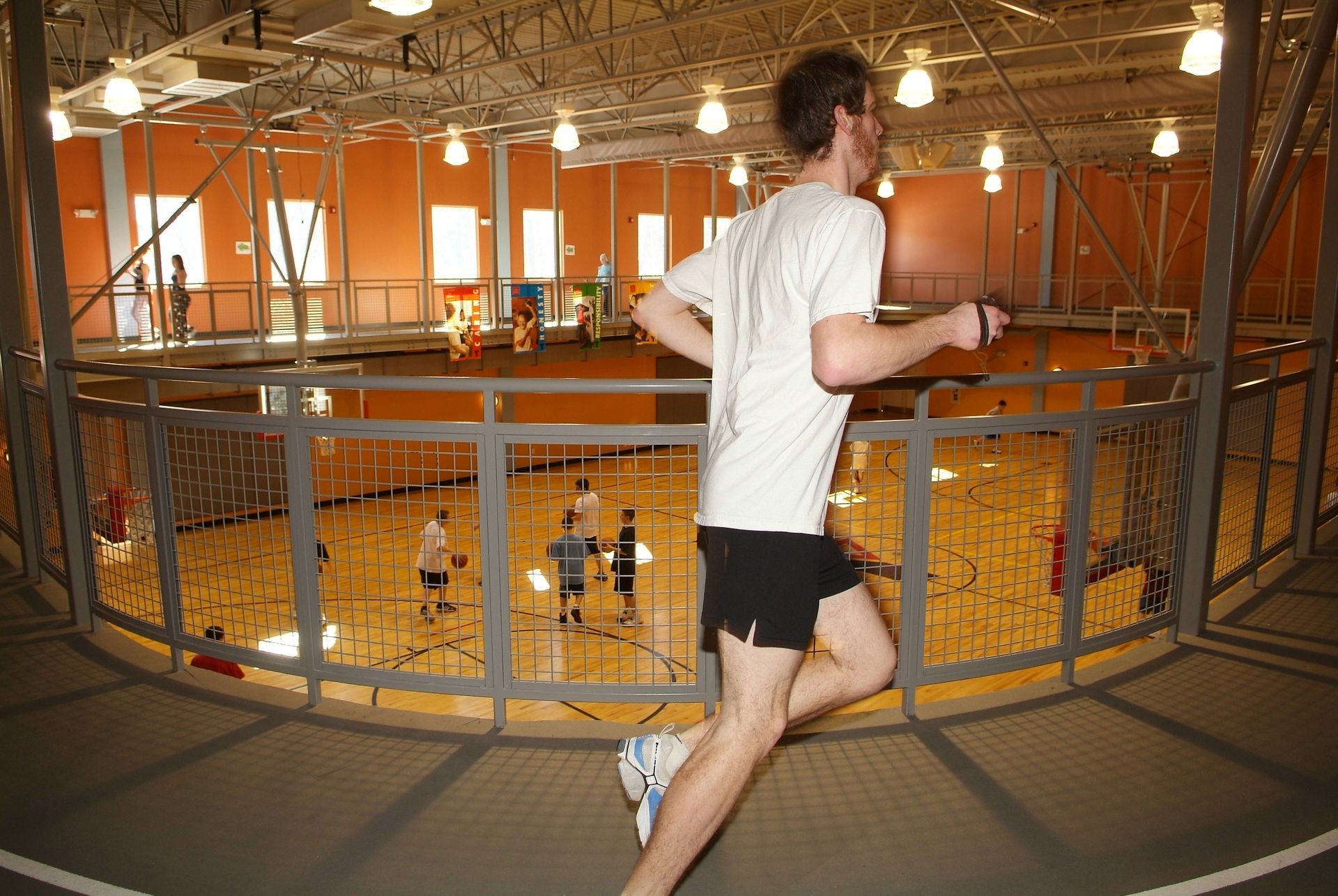 A man in a white shirt is running in a gym