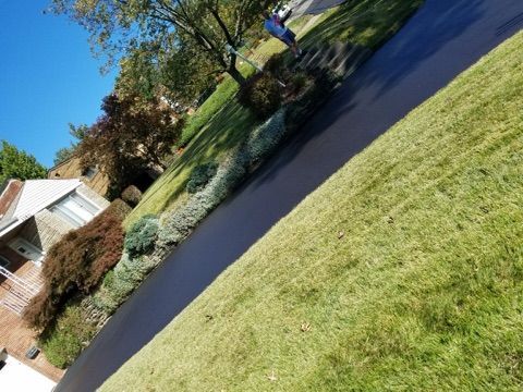 Tilted view of a suburban house, driveway, and green lawn under a bright blue sky