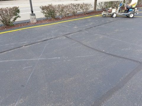 Parking lot asphalt with painted yellow curb line and a small utility cart near the edge