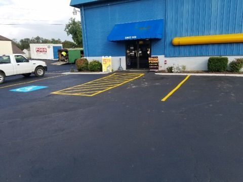 Blue building entrance with awning, yellow-striped accessible parking spaces, and a white van in the lot