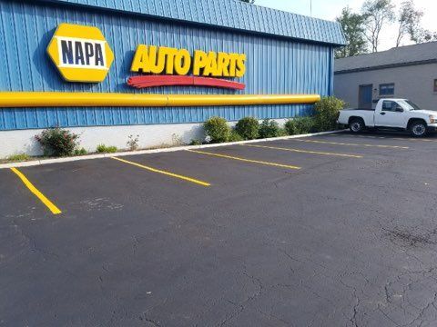 NAPA Auto Parts storefront with empty parking spaces and a white pickup truck parked beside the building