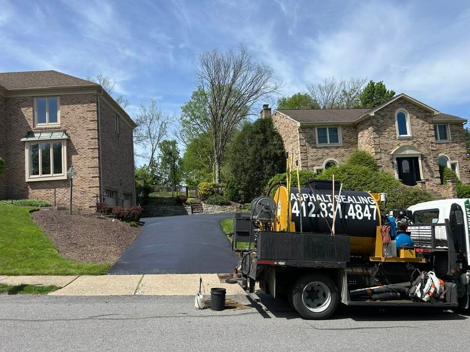 Driveway between brick houses with a black utility truck parked in front and workers nearby