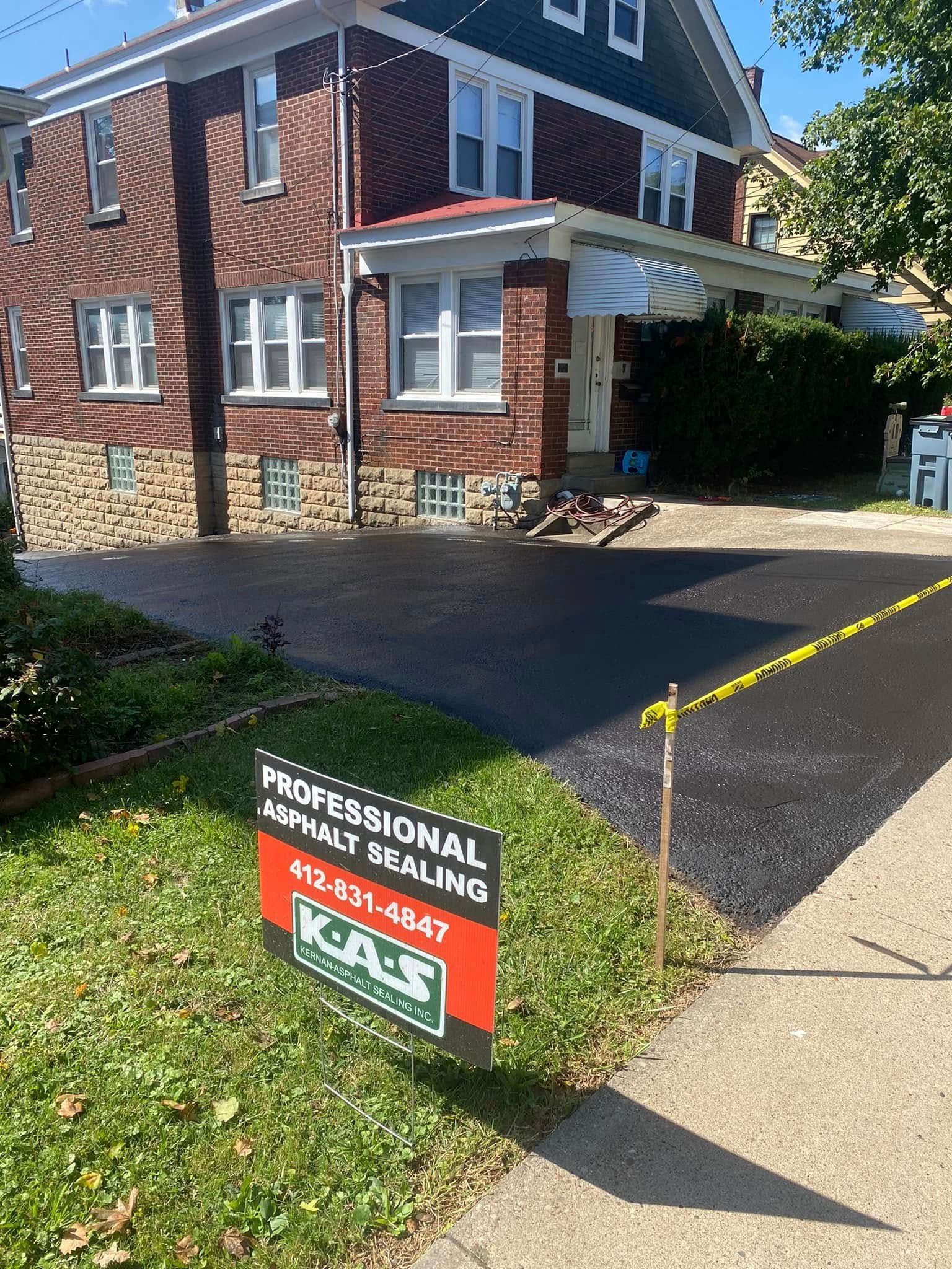 Brick house with a driveway and a yellow caution tape barrier, plus a real estate sign in front.