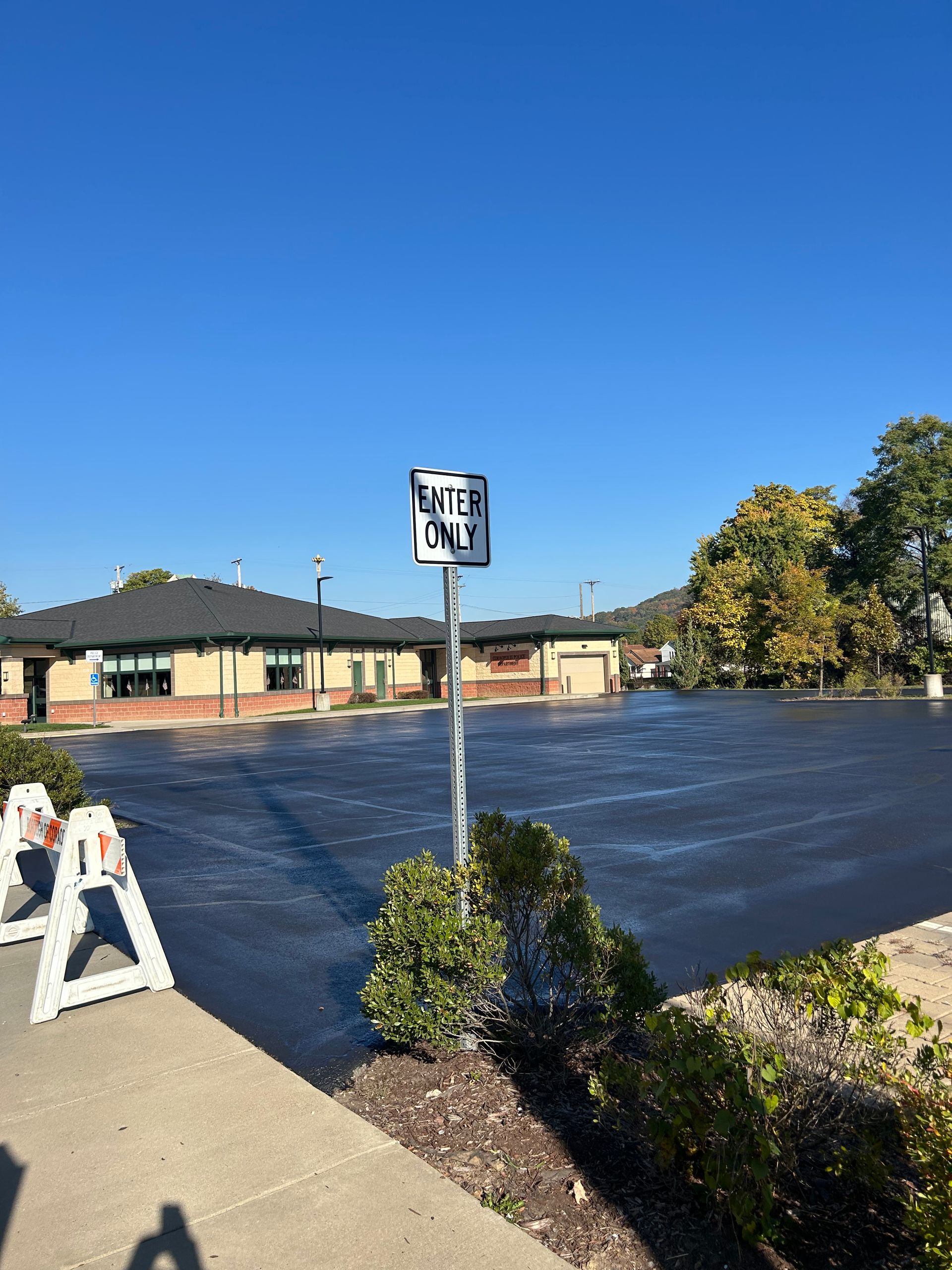 Black asphalt parking lot with a handicap sign and a building under a clear blue sky