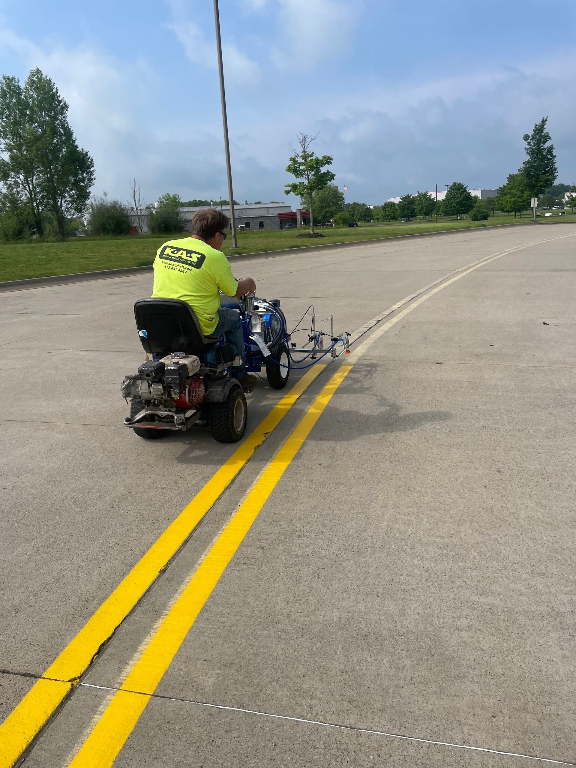 Person on a motorized wheelchair on a double yellow line in an open road, with a blue sky and trees nearby
