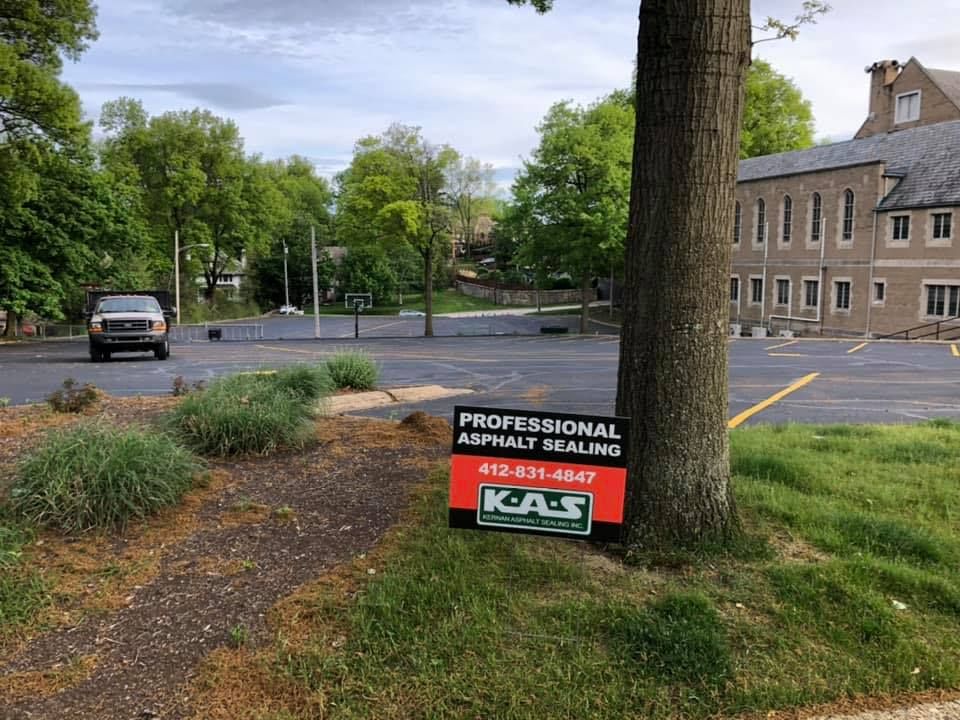 Parking lot with a tree and a sign advertising professional landscaping services