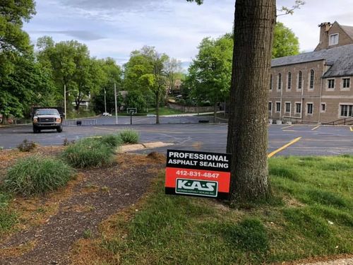 Parking lot with a tree and a sign advertising professional landscaping services