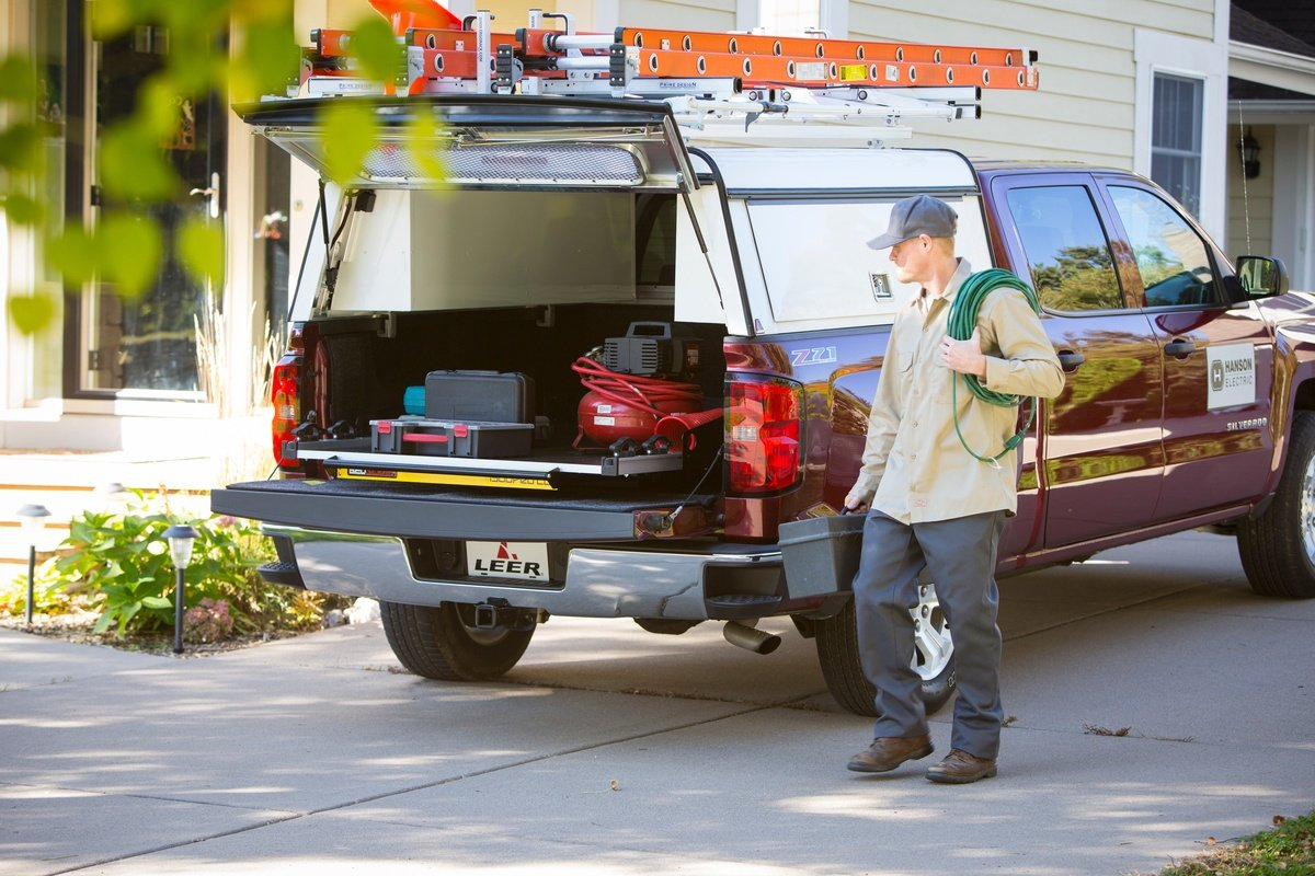 Worker with a green cord near a maroon truck with an open cap