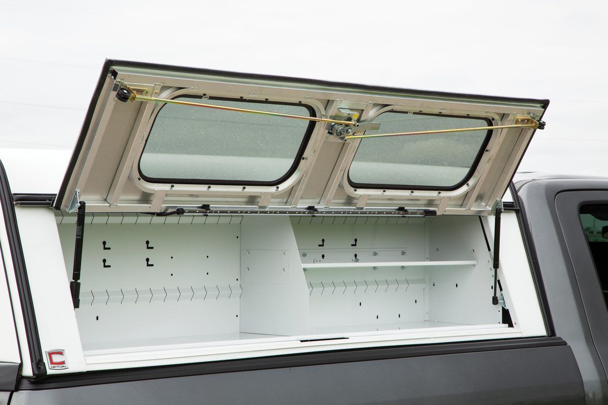 Truck bed cap with open doors revealing storage shelves.