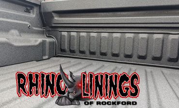 Rhino Linings truck bed with dark textured coating, company logo in foreground.