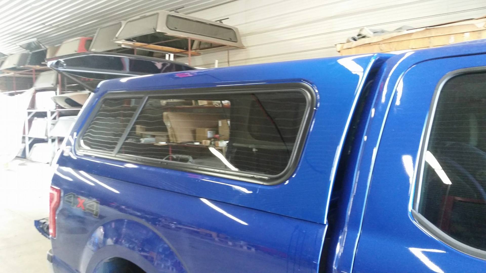Blue truck with a matching camper shell in a workshop.