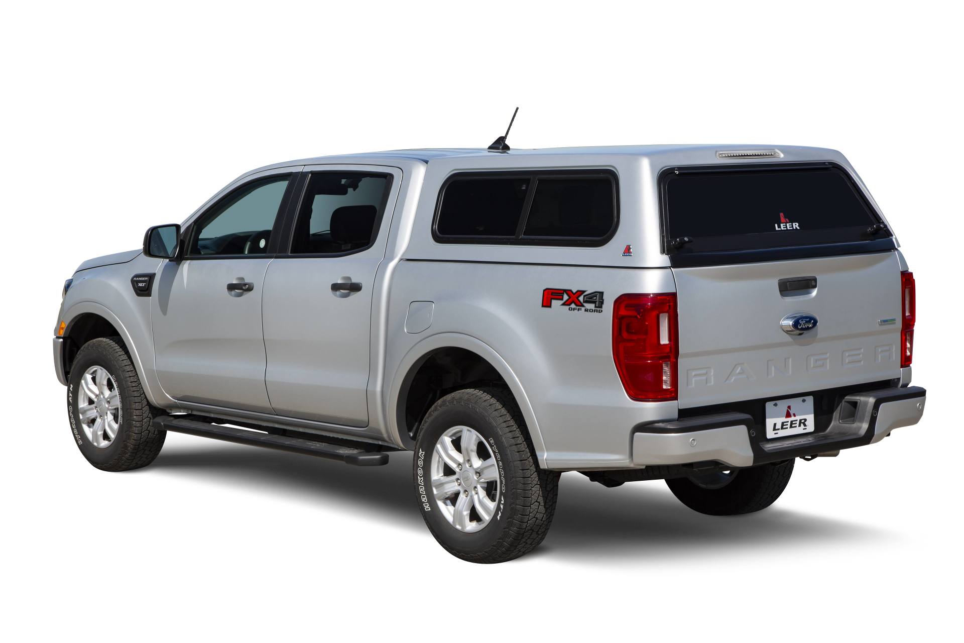 Silver Ford Ranger pickup truck with a camper shell, parked outside.