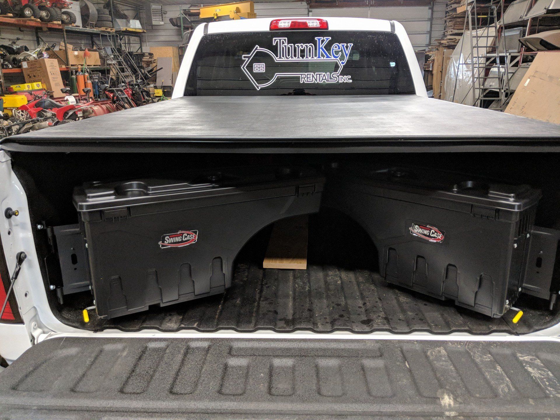 Black truck bed with two storage boxes and a rolled-up cover; 