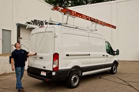 White van with ladder rack, man looking up at ladder.