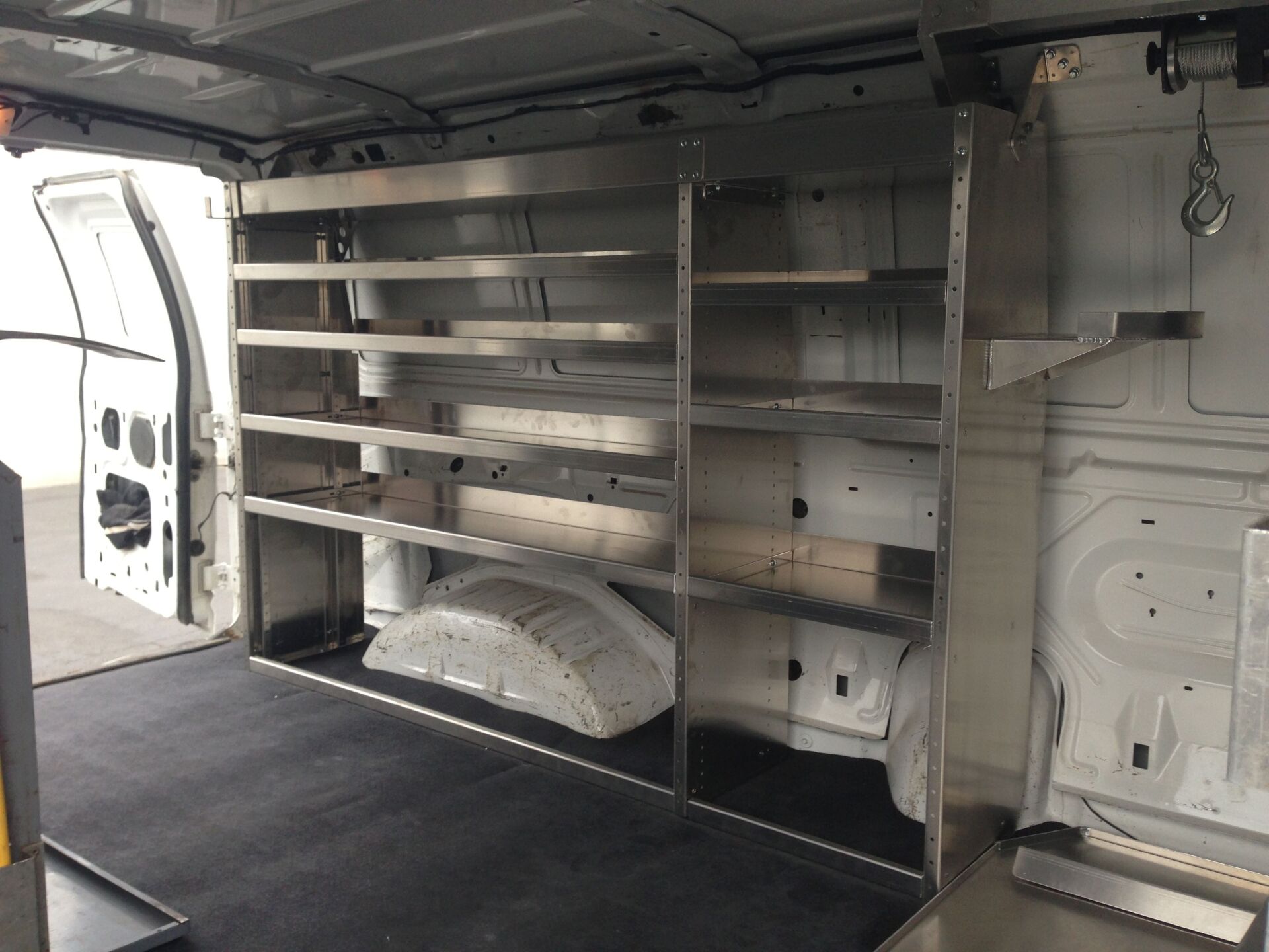 Interior view of a cargo van with stainless steel shelving along the side for storage.