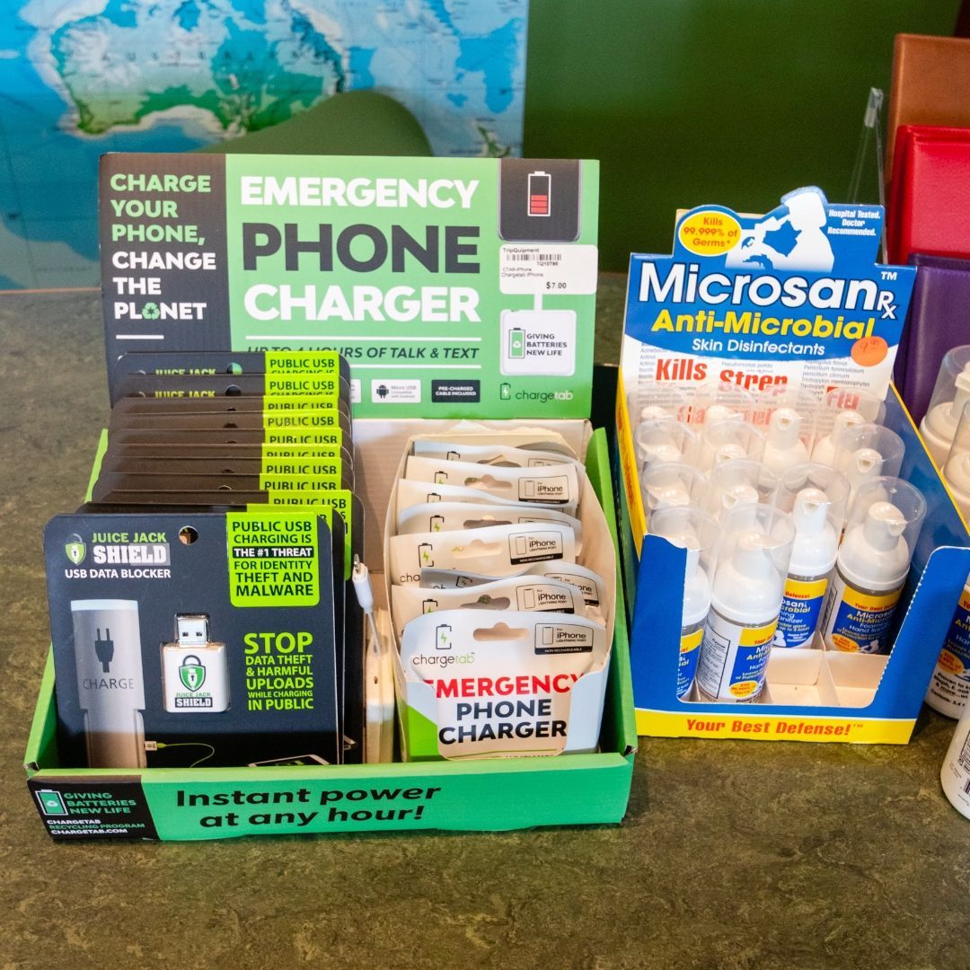 Countertop retail display featuring emergency phone chargers in green boxes and Microsan anti-microbial spray bottles.