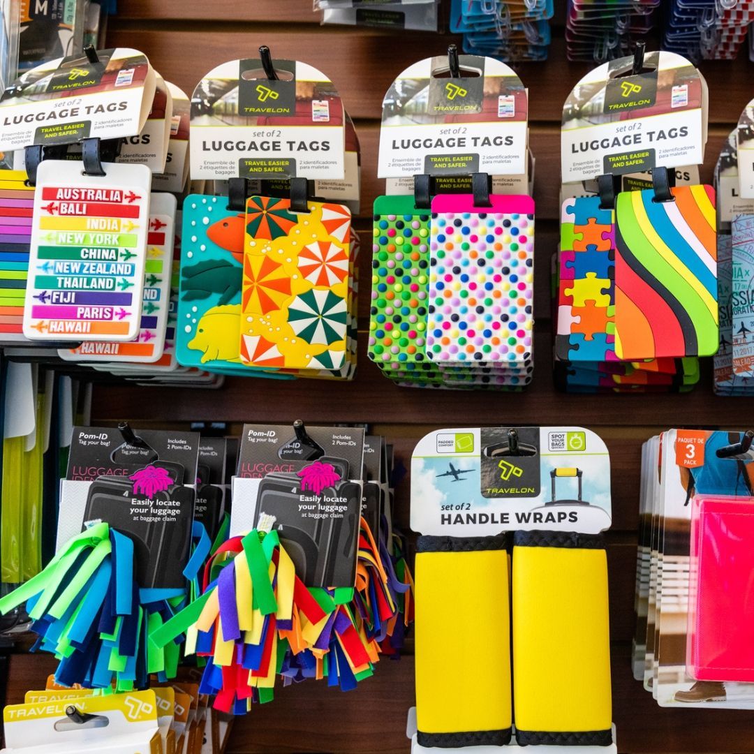 A display rack featuring colorful, patterned luggage tags and vibrant yellow suitcase handle wraps.
