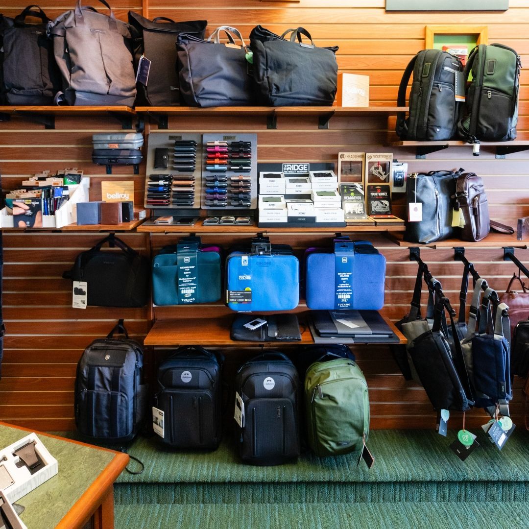A store display wall featuring various backpacks, bags, and small accessories organized on wooden shelves.