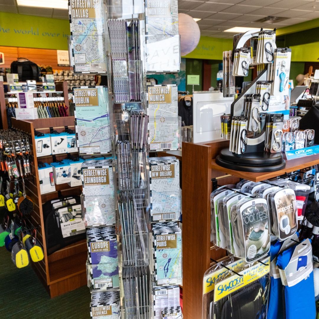 A retail store display featuring vertical racks filled with various packaged goods, including maps and small accessories.