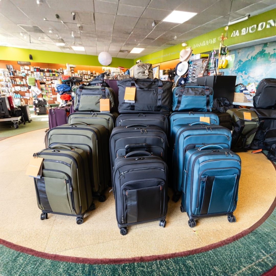 A display of assorted olive and blue rolling suitcases and travel bags arranged on a circular rug in a retail store.