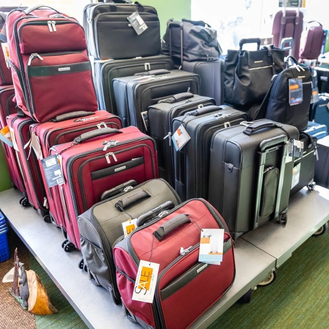 An assortment of maroon and black travel suitcases and carry-on bags displayed on a store table.