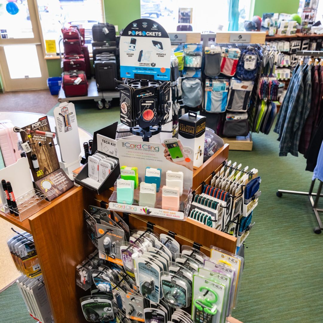 A retail display filled with phone cases and accessories, featuring a central PopSockets stand, in a store aisle.