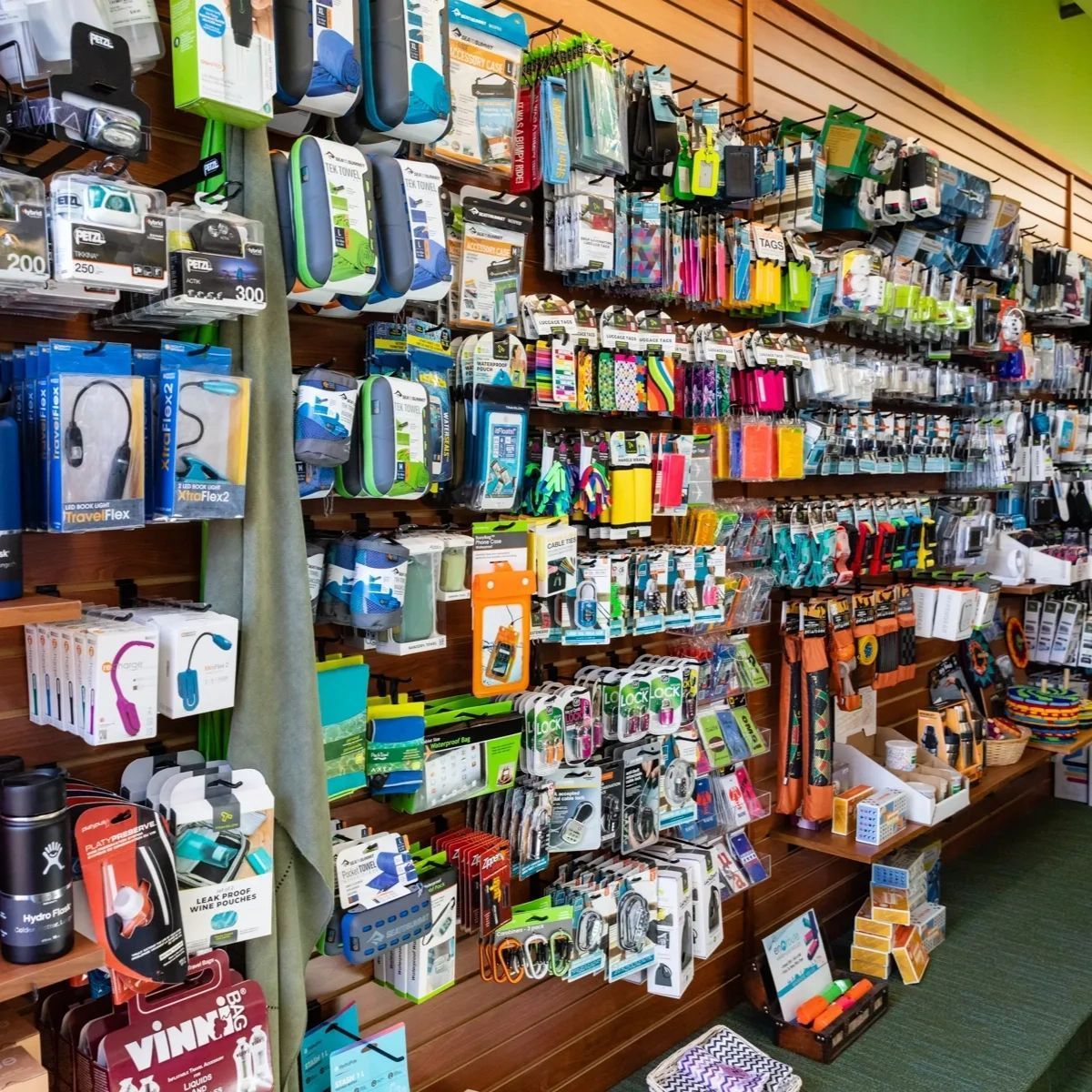 A retail store wall display filled with various tech accessories, including charging cables, cases, and small gadgets.