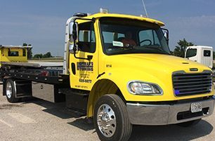 Learn more about Towing Service Yellow tow truck parked outdoors on a sunny day.