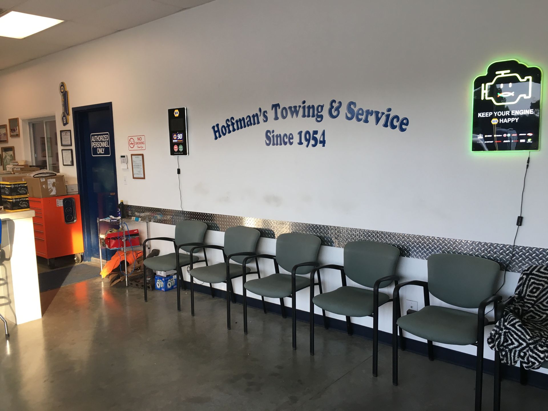 Interior of Hoffman's Towing & Service waiting area with chairs and a check engine light sign.
