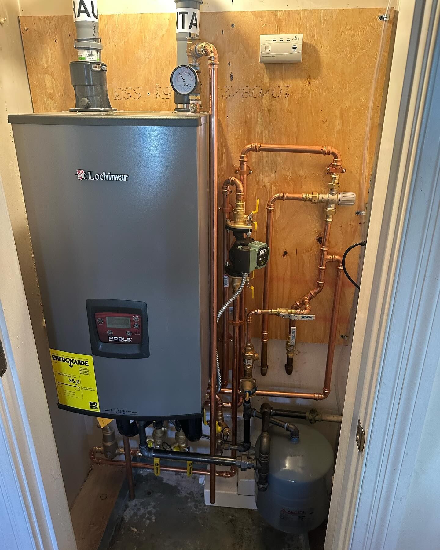A room with a water heater and copper pipes.