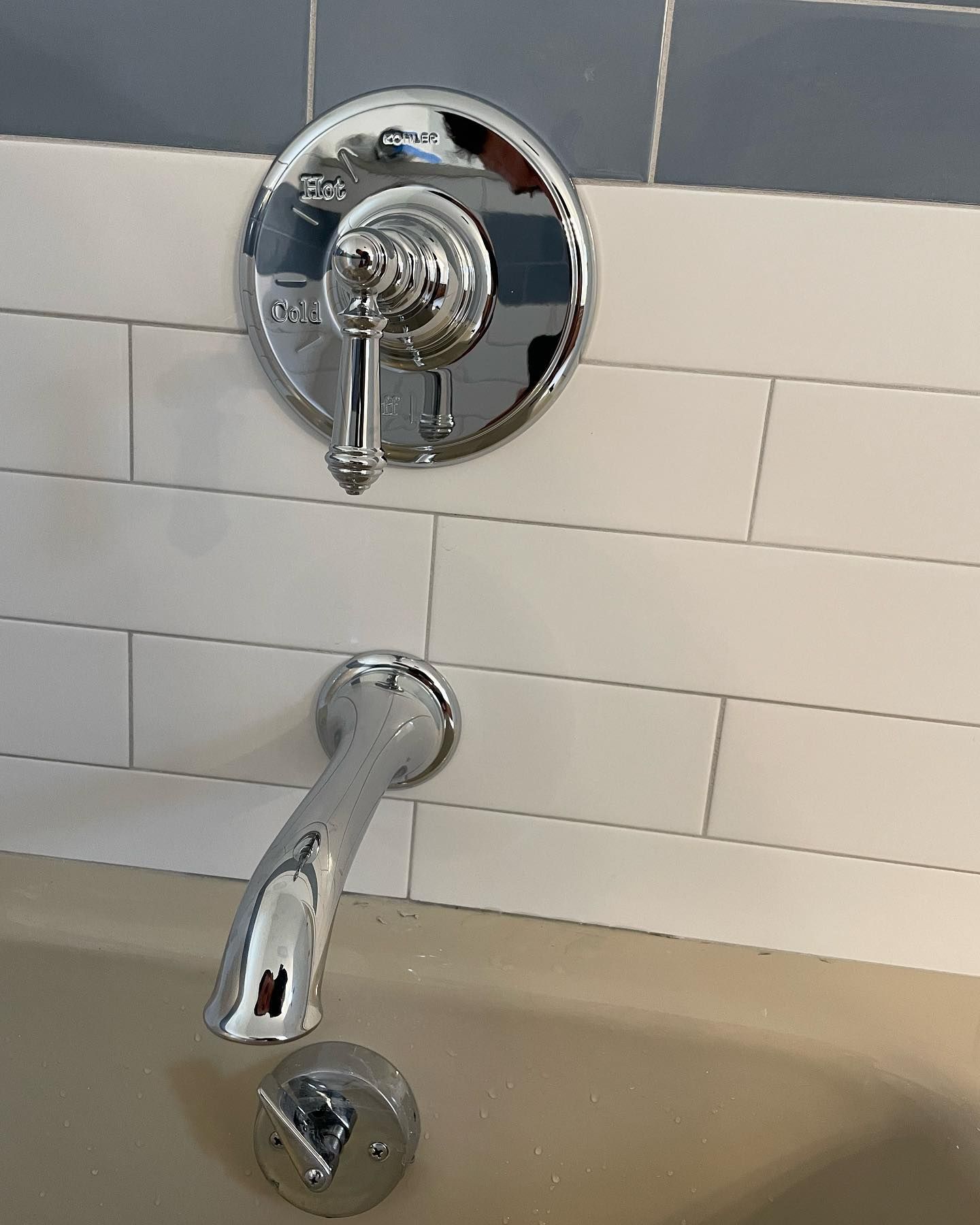 A chrome shower head is mounted to a white tiled wall.