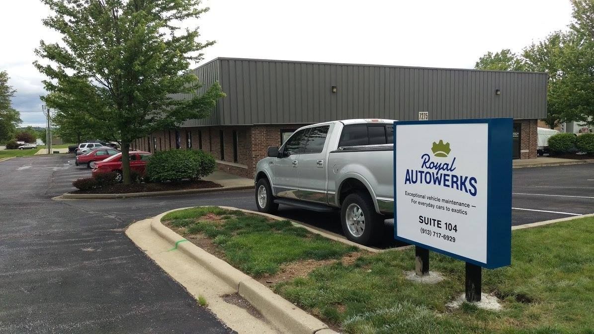 Royal Autowerks sign in front of a gray building, silver pickup truck parked nearby.
