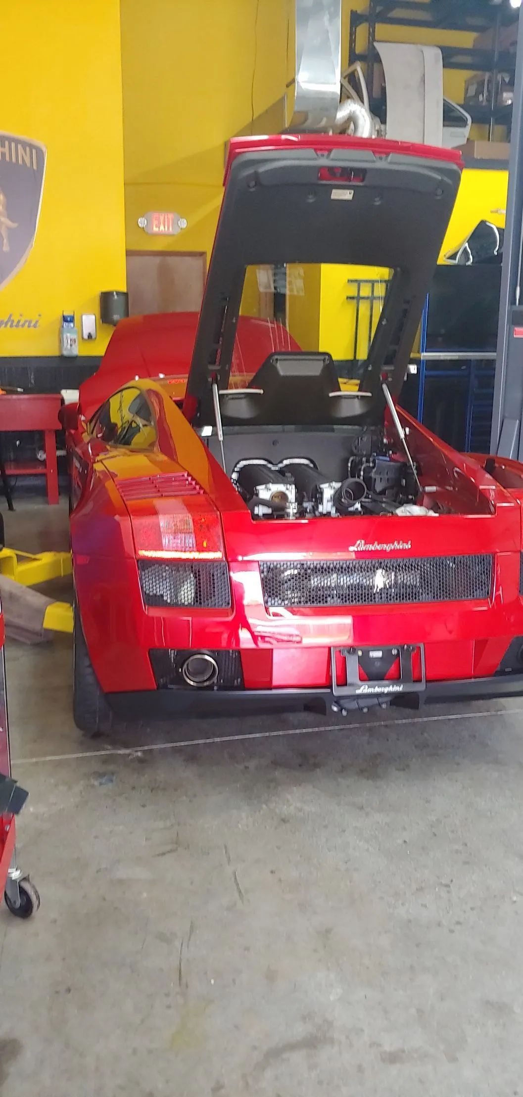 Red Lamborghini with open hood in a garage.