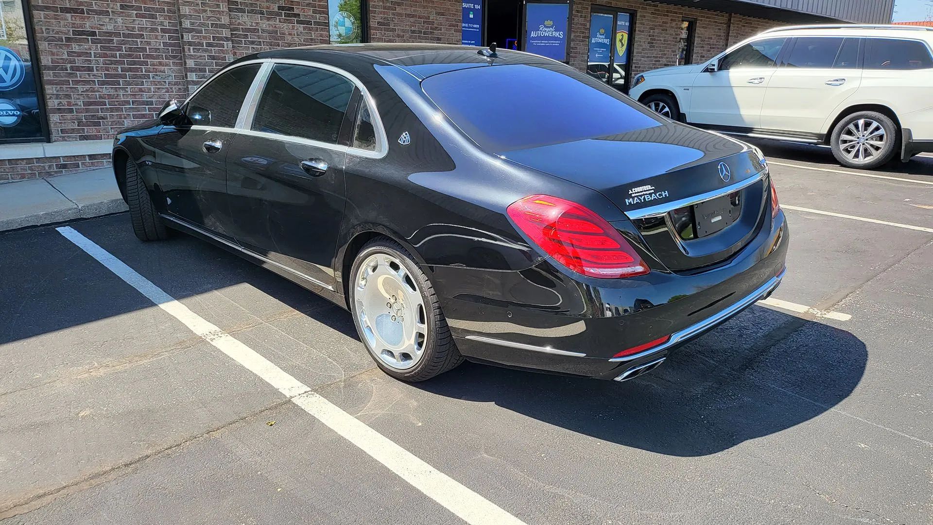 Black Mercedes-Maybach sedan parked in a parking lot, tinted windows, chrome accents, and light-colored rims.